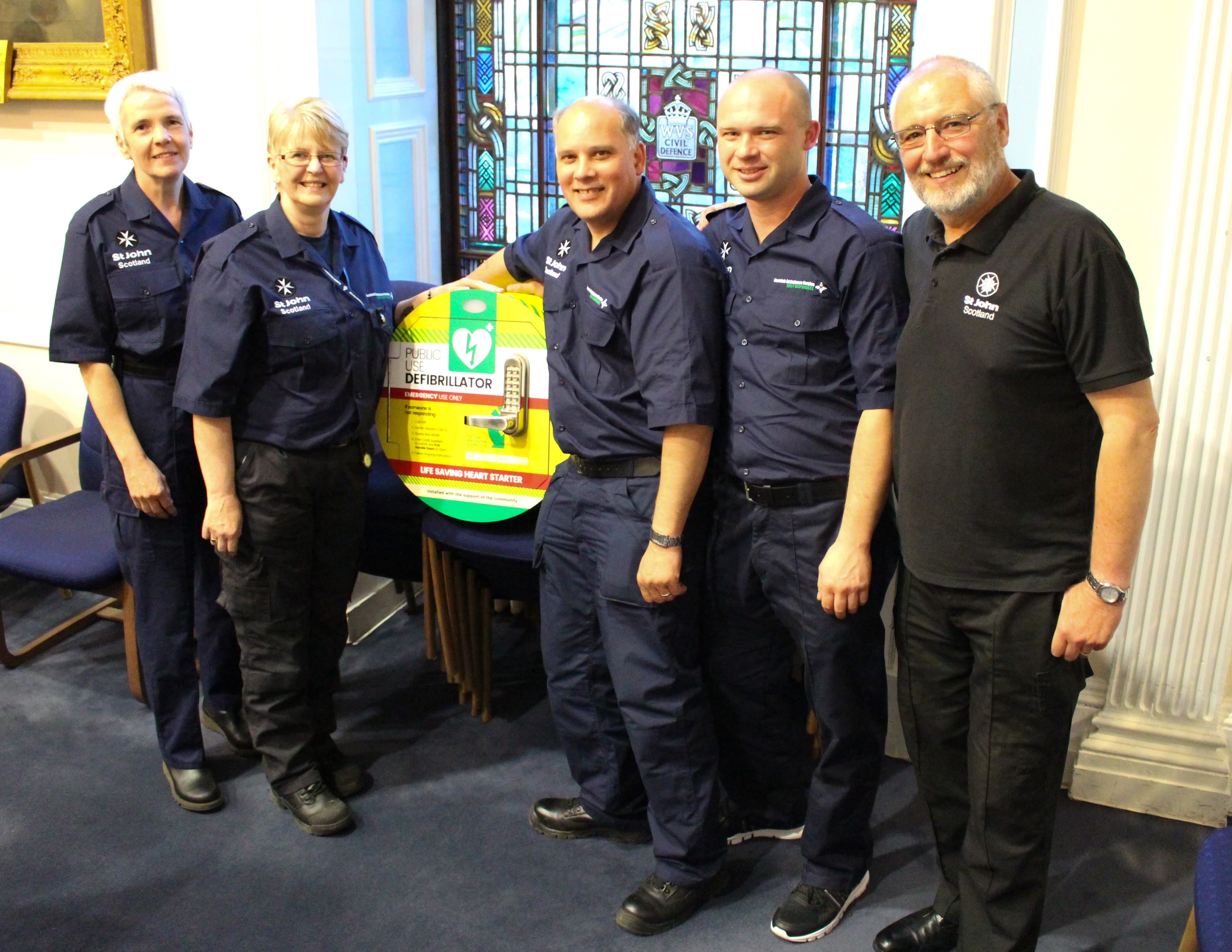 Photo of first responders beside a defibrillator 