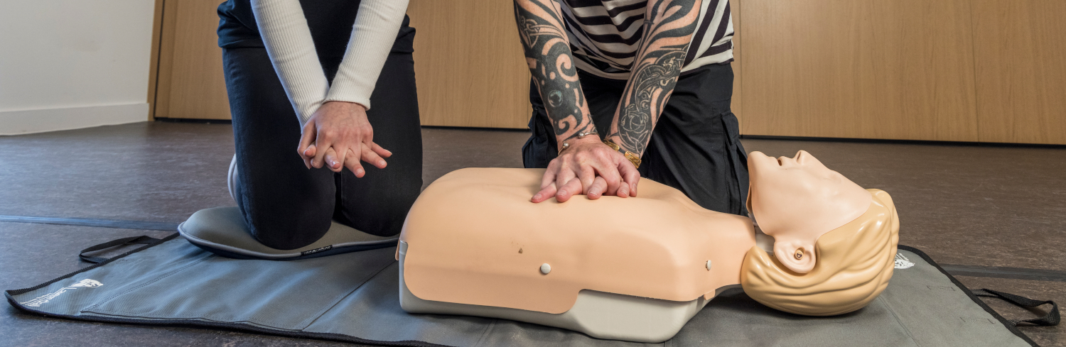 A pair of hands perform CPR on a manikin