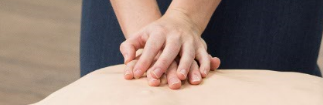 A pair of hands perform CPR on a manikin