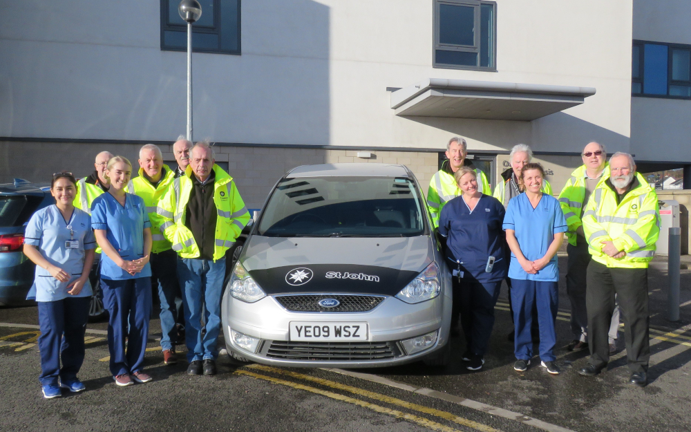 A group of people stand next to a car