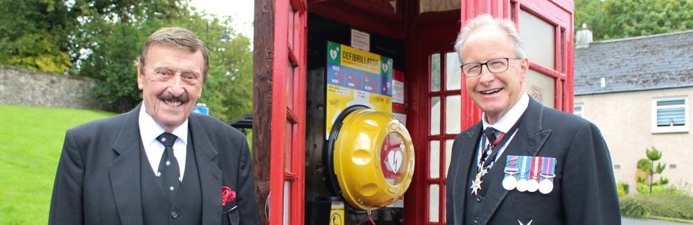 Two men stand next to a public access defibrillator