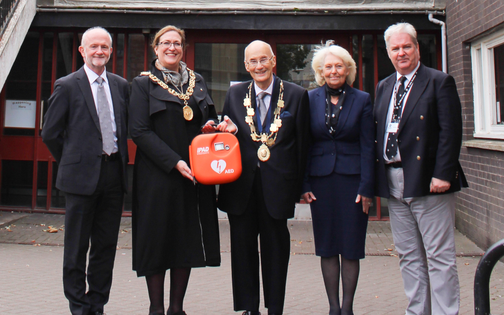 A group of people pose with a defibrillator 