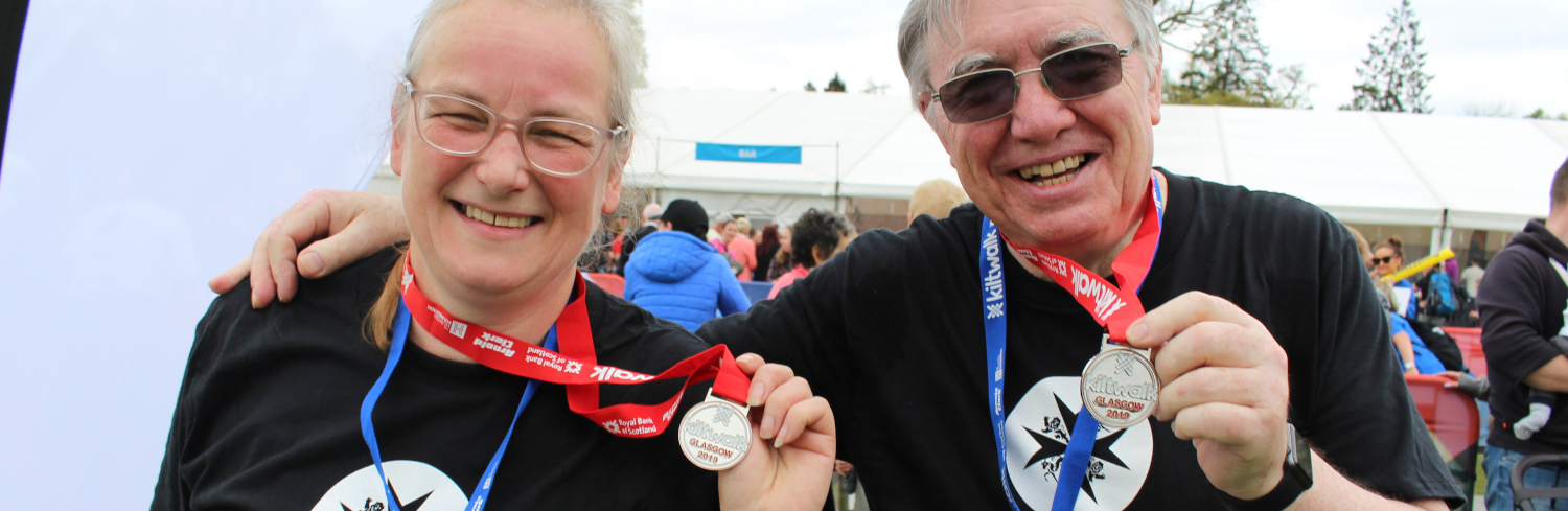Two people pose with Kiltwalk medals
