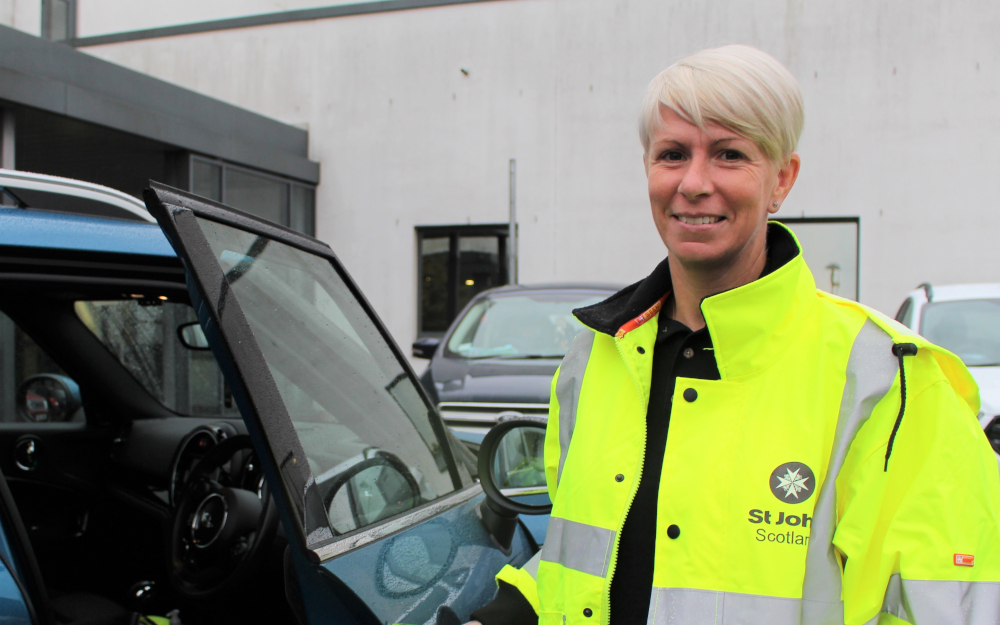 A woman stands next to a car