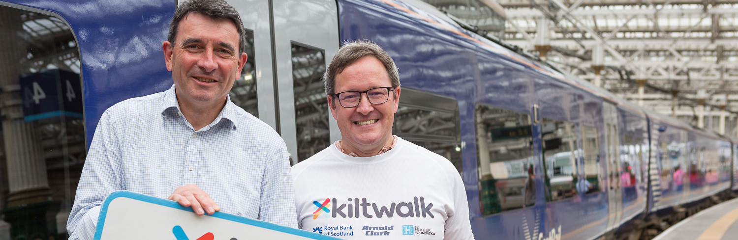 Two men pose in front of a train