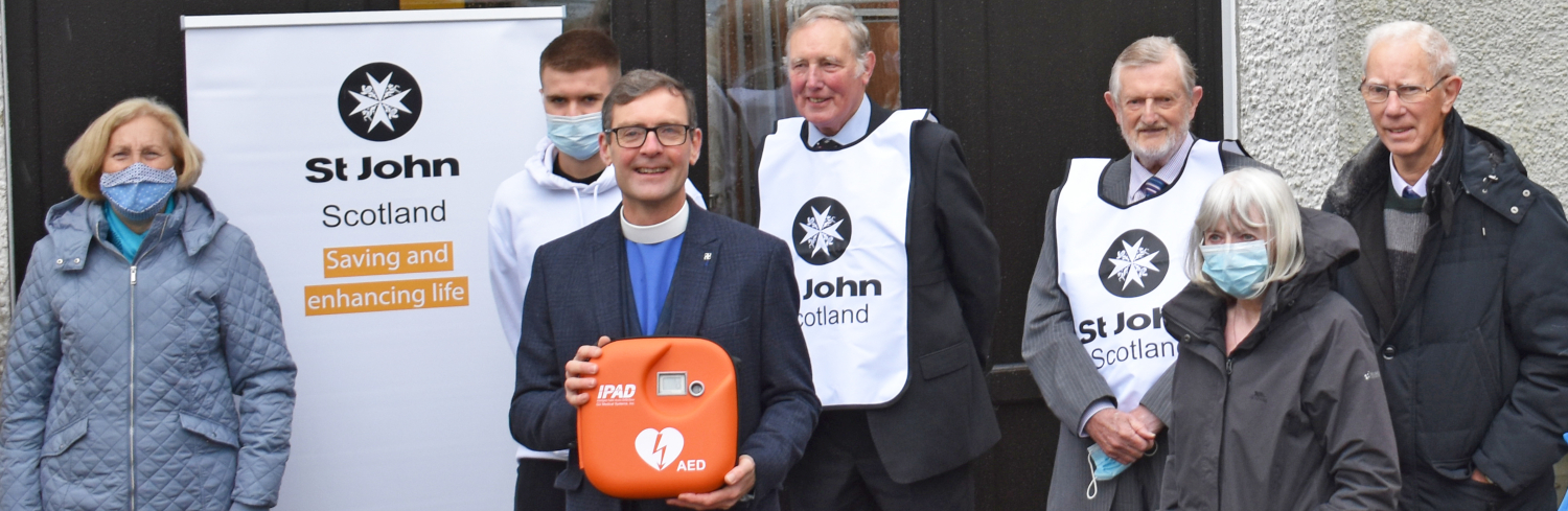 A group of people pose with a defibrillator