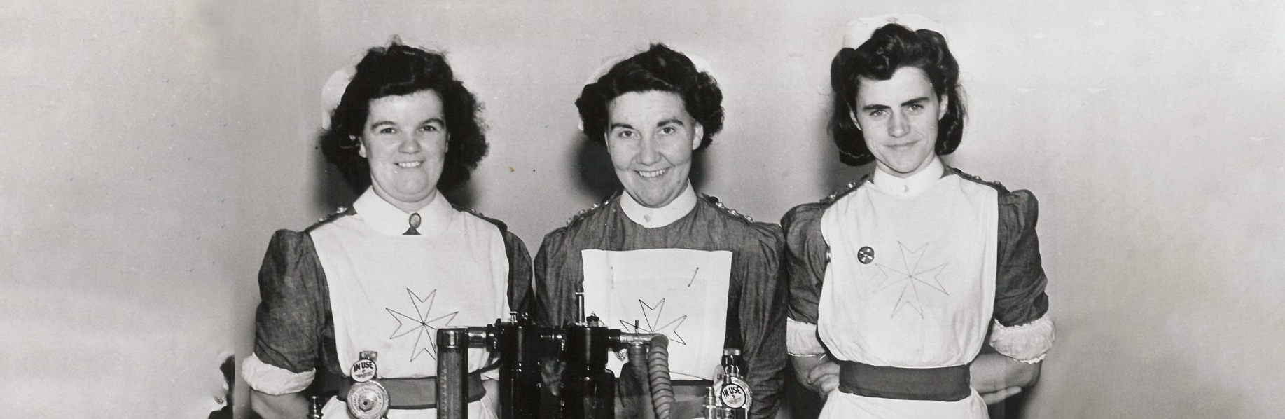 A black and white photograph of three women wearing nurses' uniforms