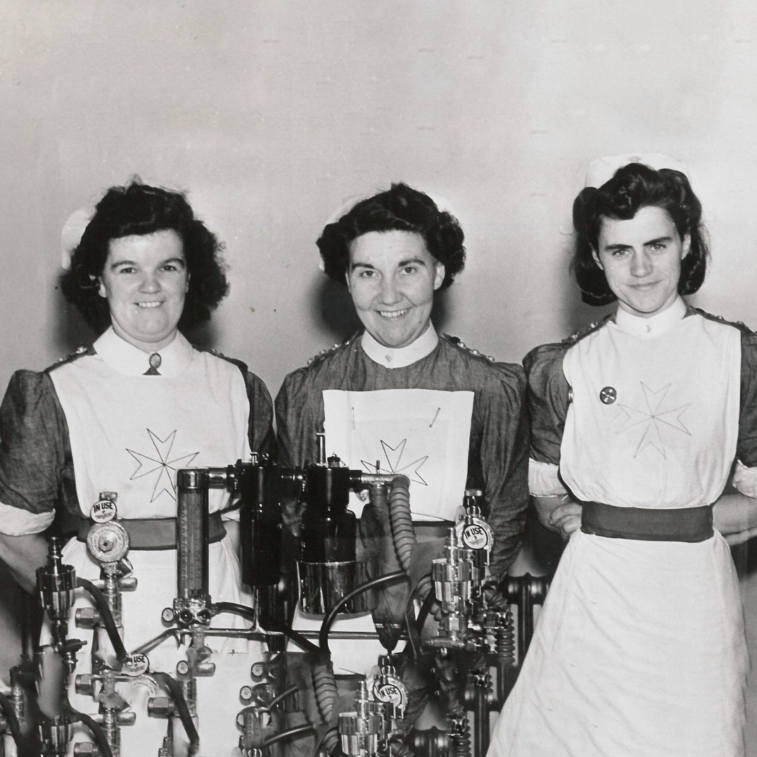 A black and white photograph of three women wearing nurses' uniforms