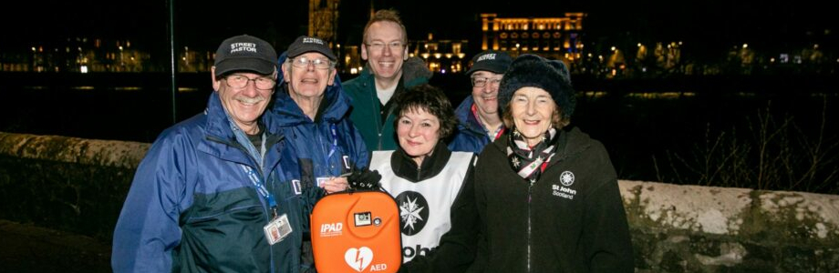 A group of people pose with a defibrillator