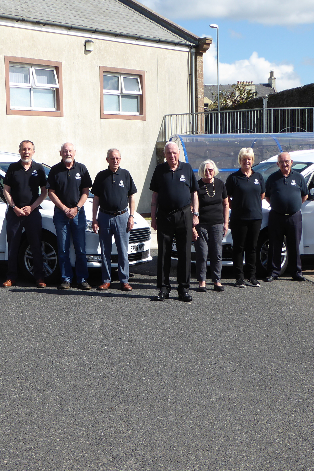 A group of St John Scotland volunteers with two cars