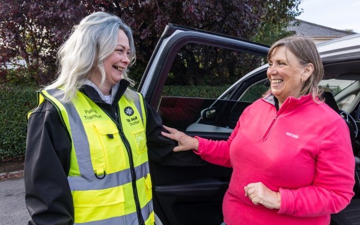 A woman in hi vis and a woman in a pink top stand next to a car