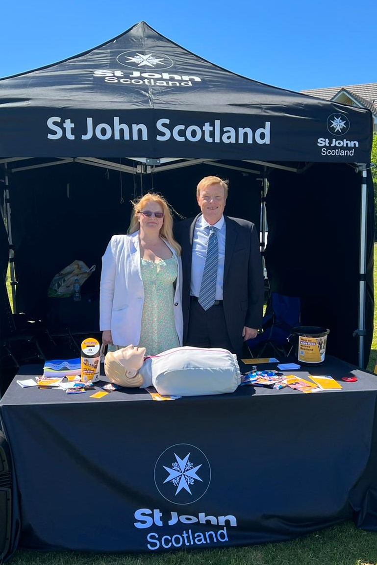 Two St John Scotland volunteers stand in front of a gazebo