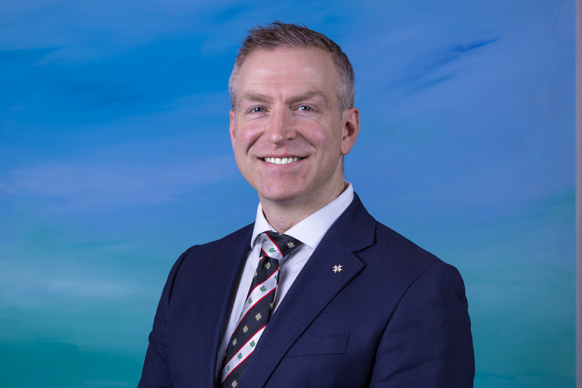 A man in a suit in front of a blue background