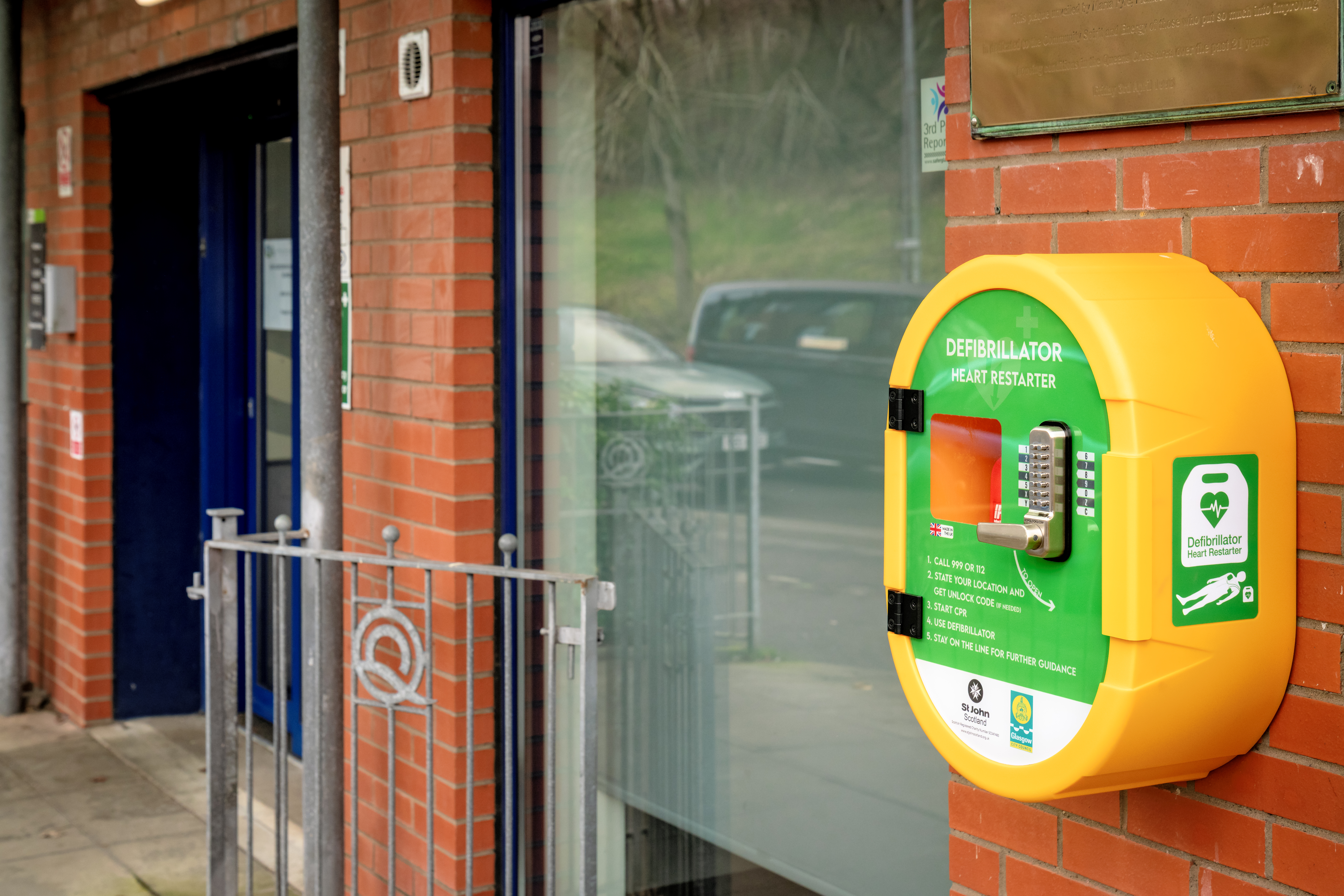 A defibrillator case with the defib inside, outside a building