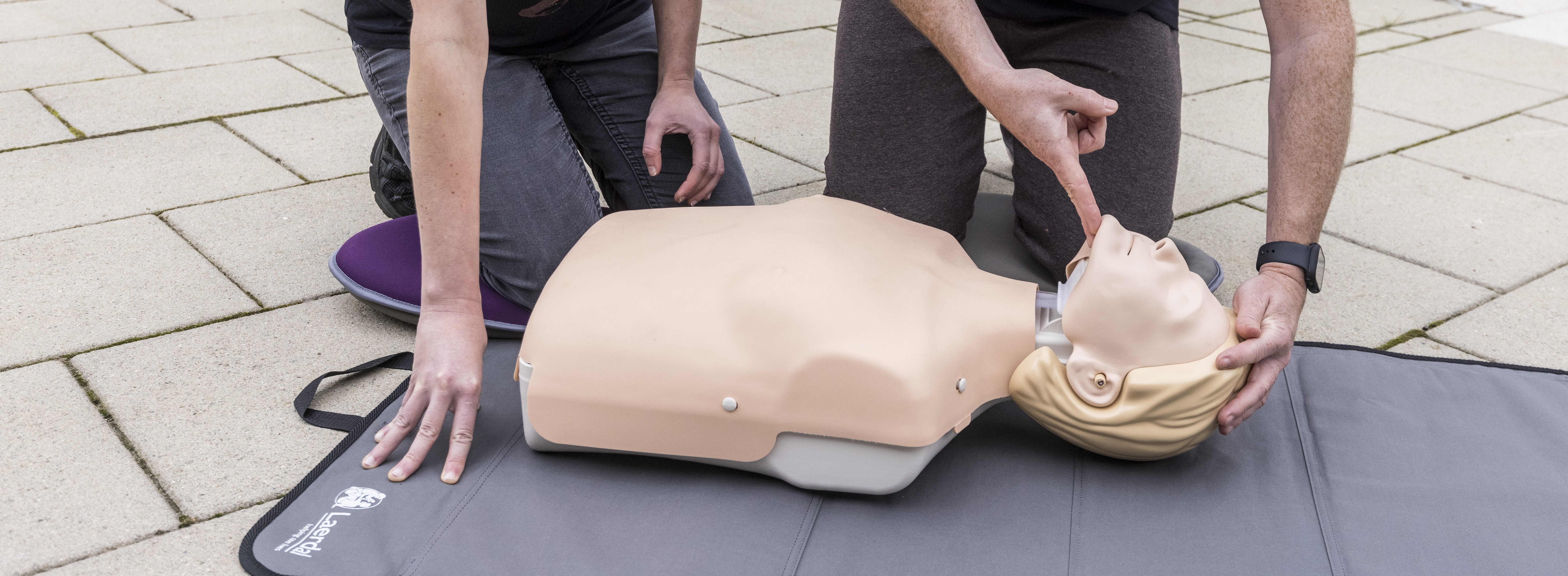 A CPR mannequin lies on a mat