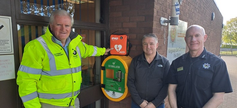 3 men stand around a defibrillator