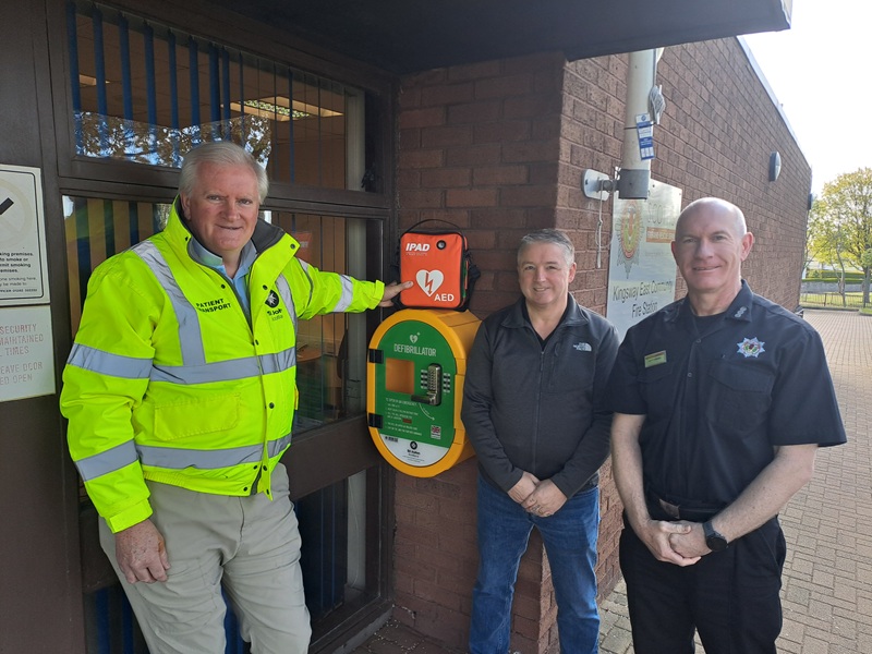 3 men stand around a defibrillator