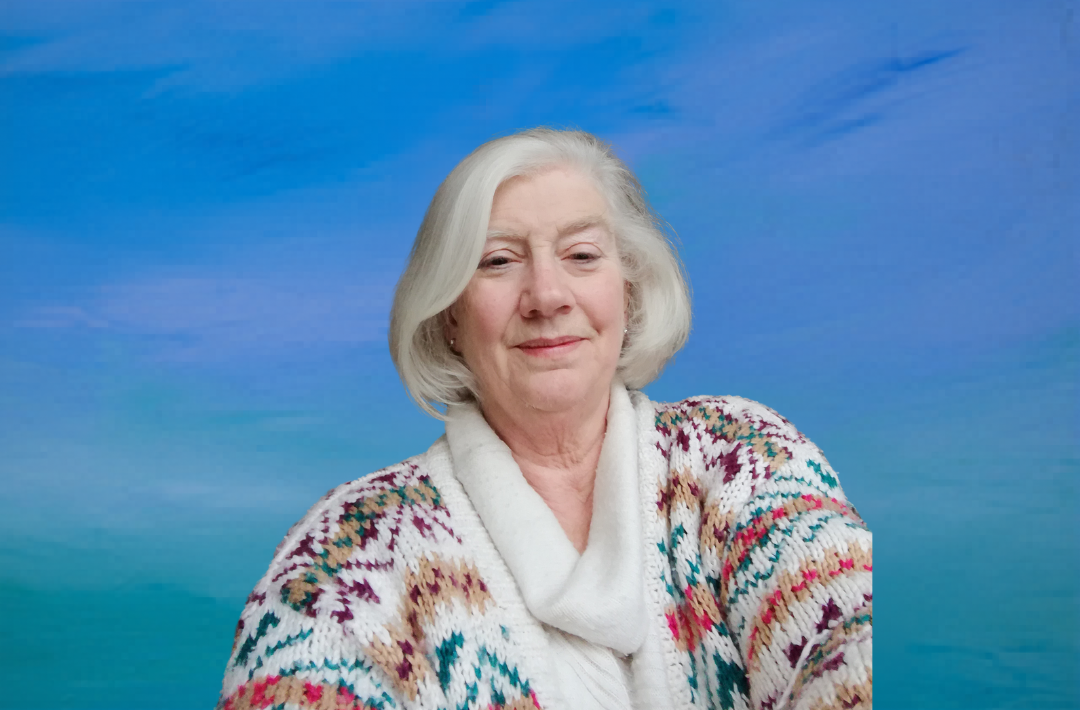 A woman in a cardigan sits in front of a blue background